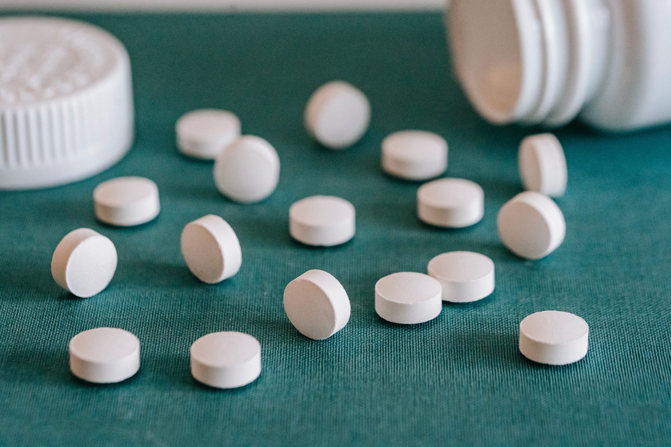 white circular pills spilled out of a medicine bottle