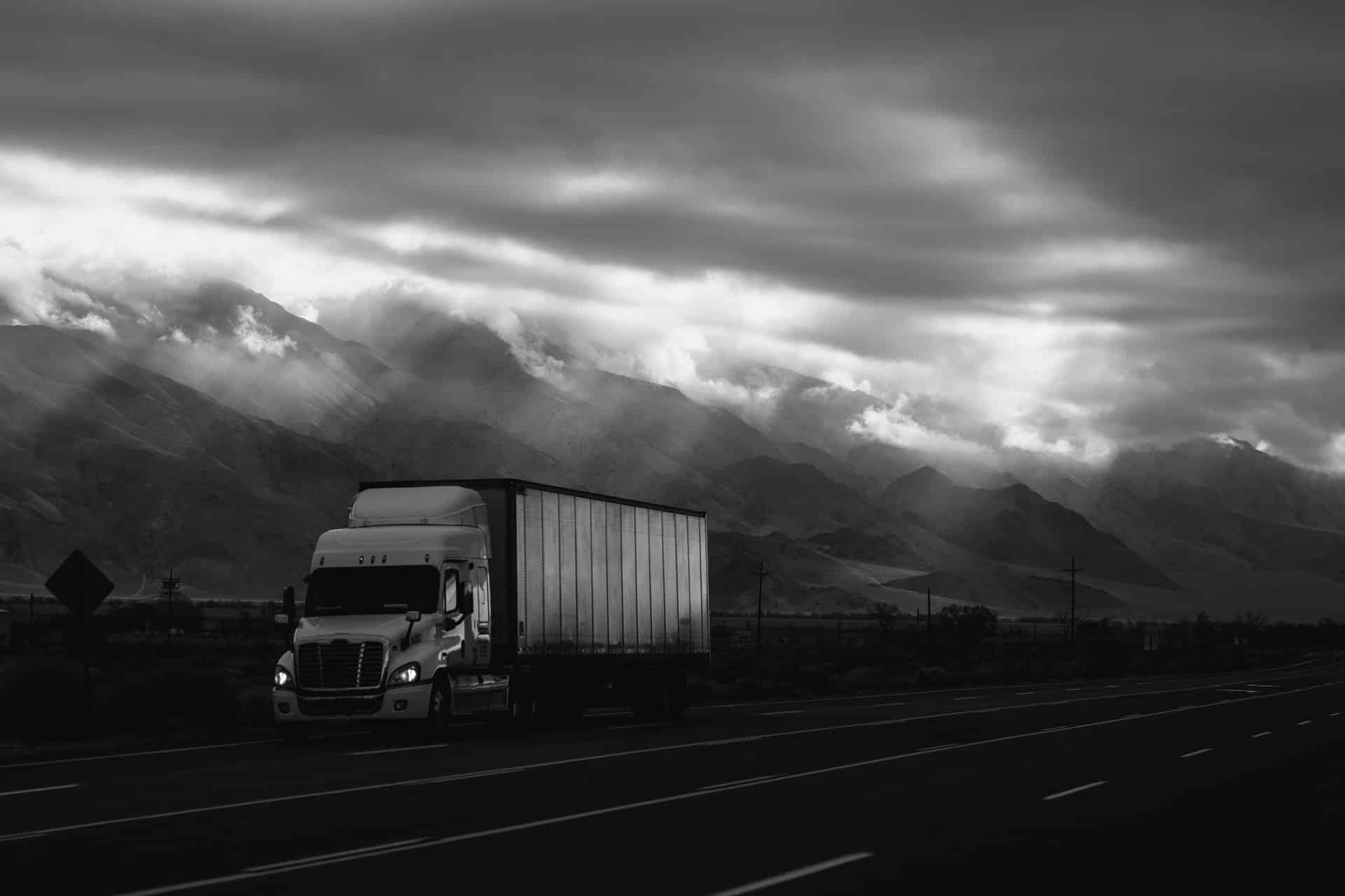 commercial truck driving on highway past mountains