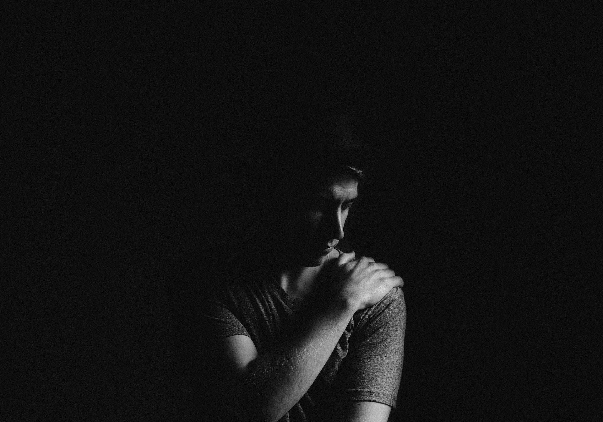 black and white photo of a man holding shoulder