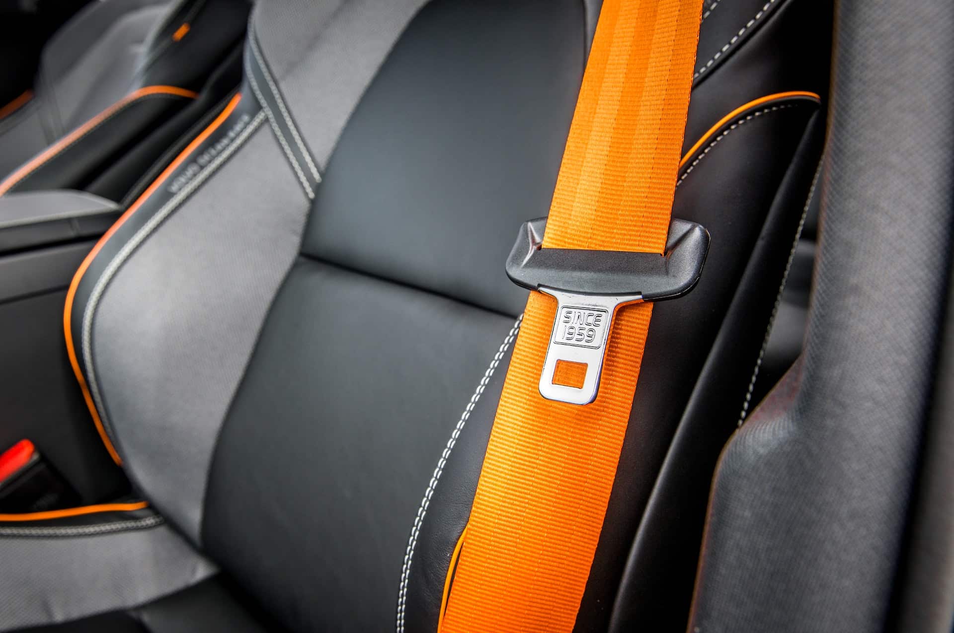 orange seat belt with black buckle in a car