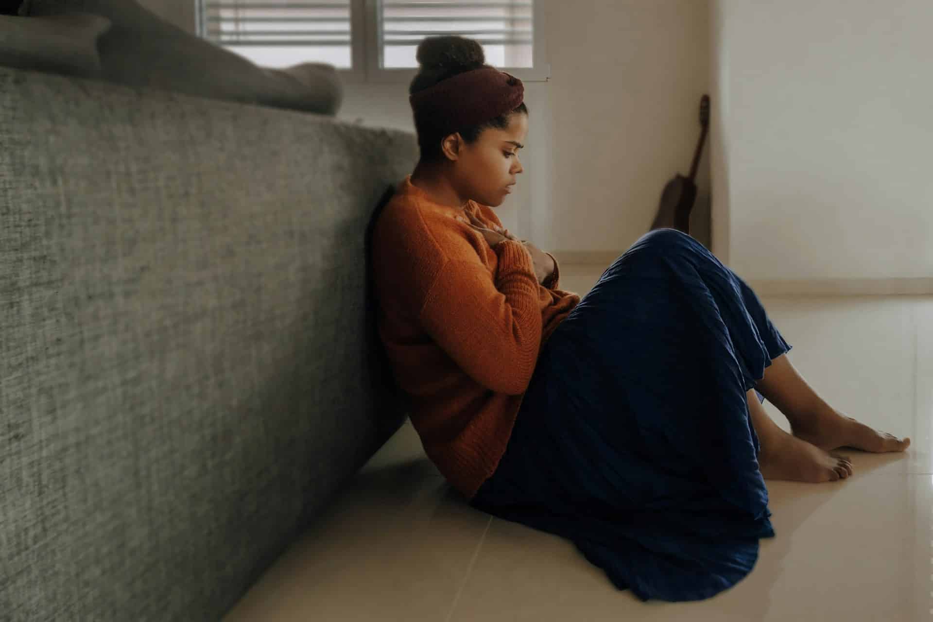 a person in orange long sleeve shirt leaning against couch