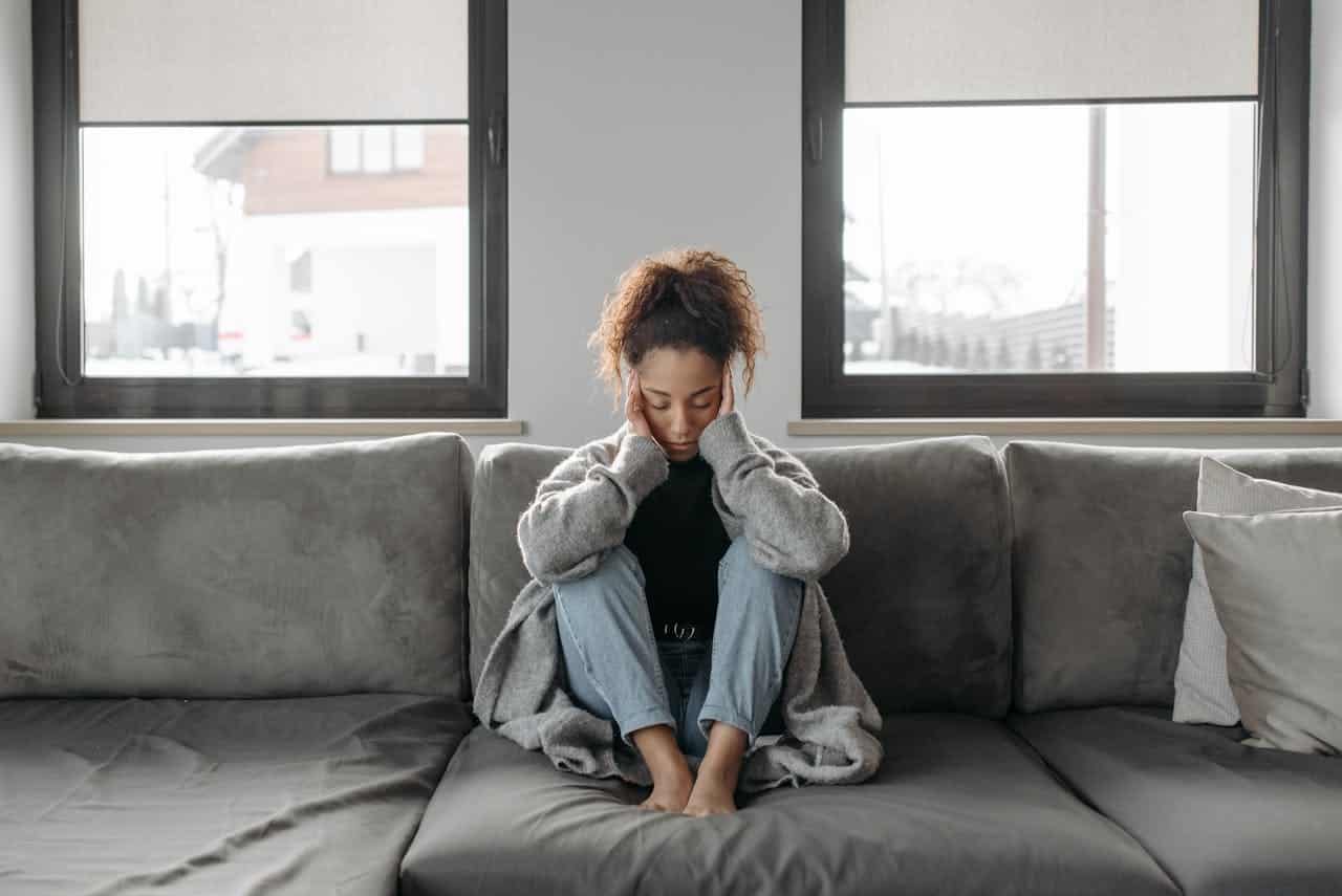 woman sitting on sofa with head in hands