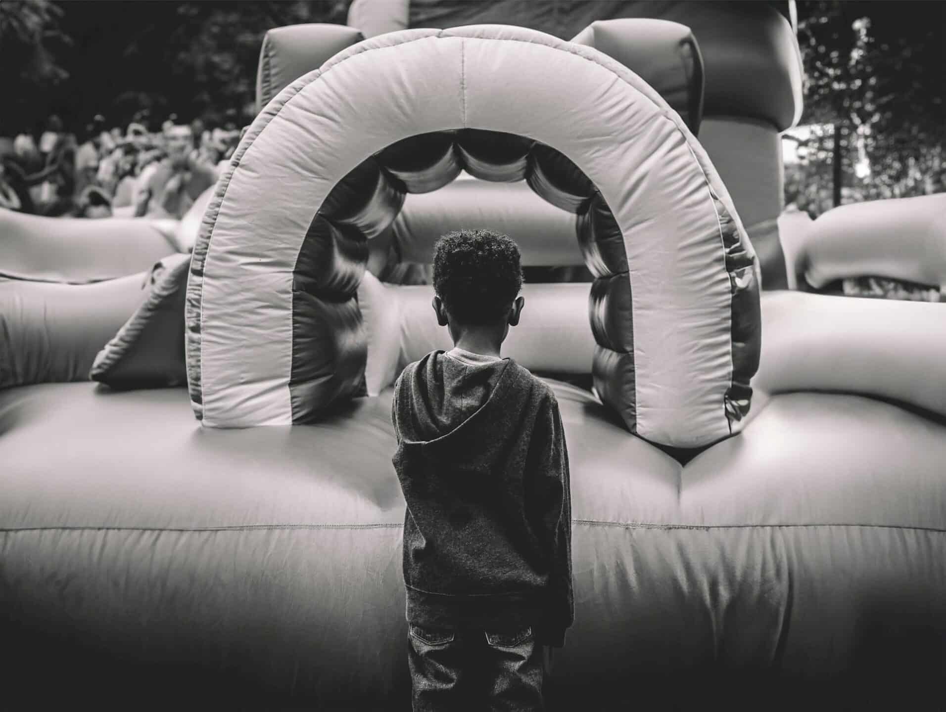 a young boy standing in front of a bounce house