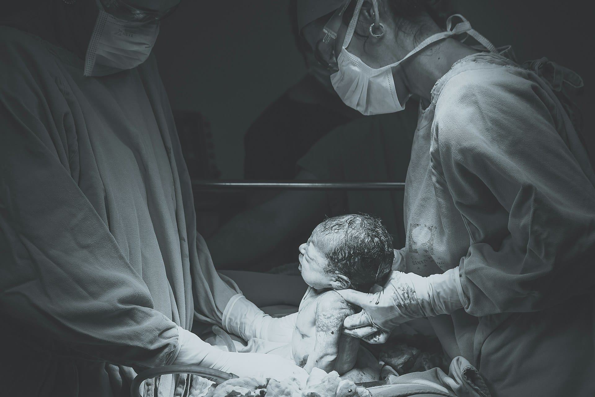 A black and white photo of two medical professionals deliverying a baby in an operating room representing the devistating affects of hypoxic-ischemic encephalopath (HIE) in birth injuries.