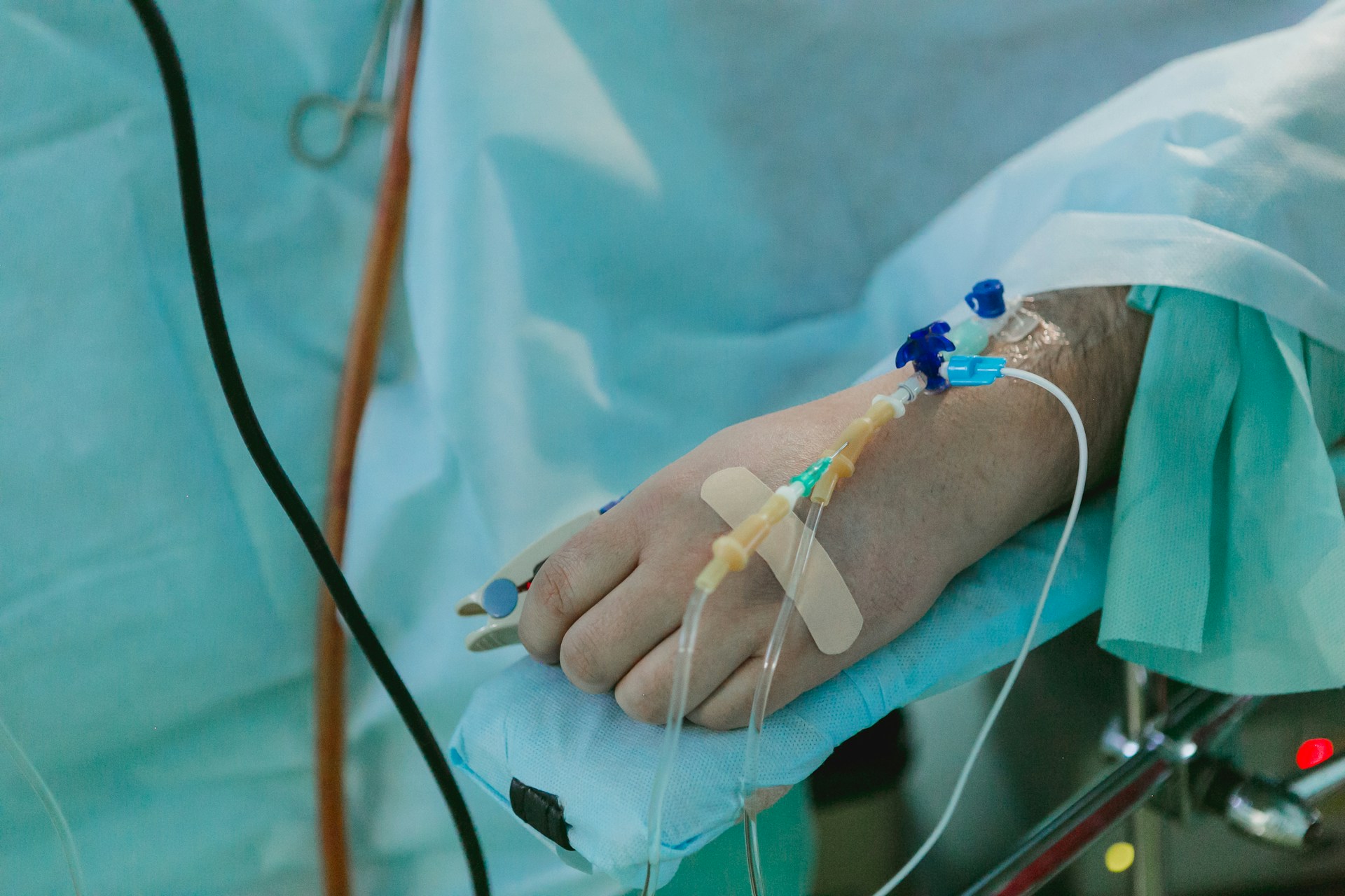 The hand of a person lying in a hospital bed with the tubes from an IV drip taped to it, representing propofol overdose malpractice.