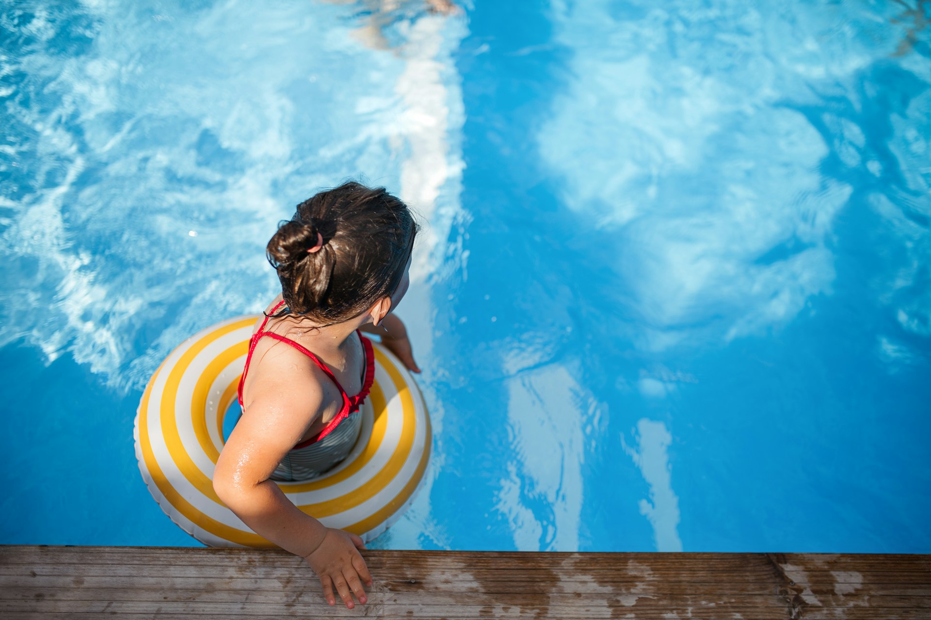 A top view of a small child in a swimming pool with a floaty ring representing drowning prevention in Alberta.
