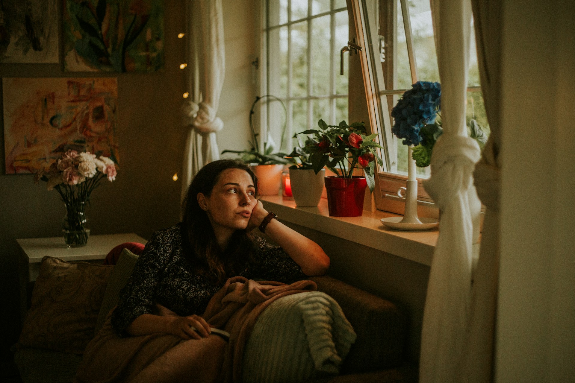 A woman wrapped in a blanket looks out her window wistfully, representing LTD and autoimmune diseases.